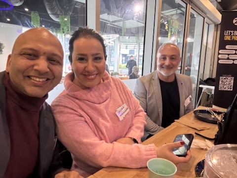 Three BGN Bundoora members close together, warmly smiling at the table