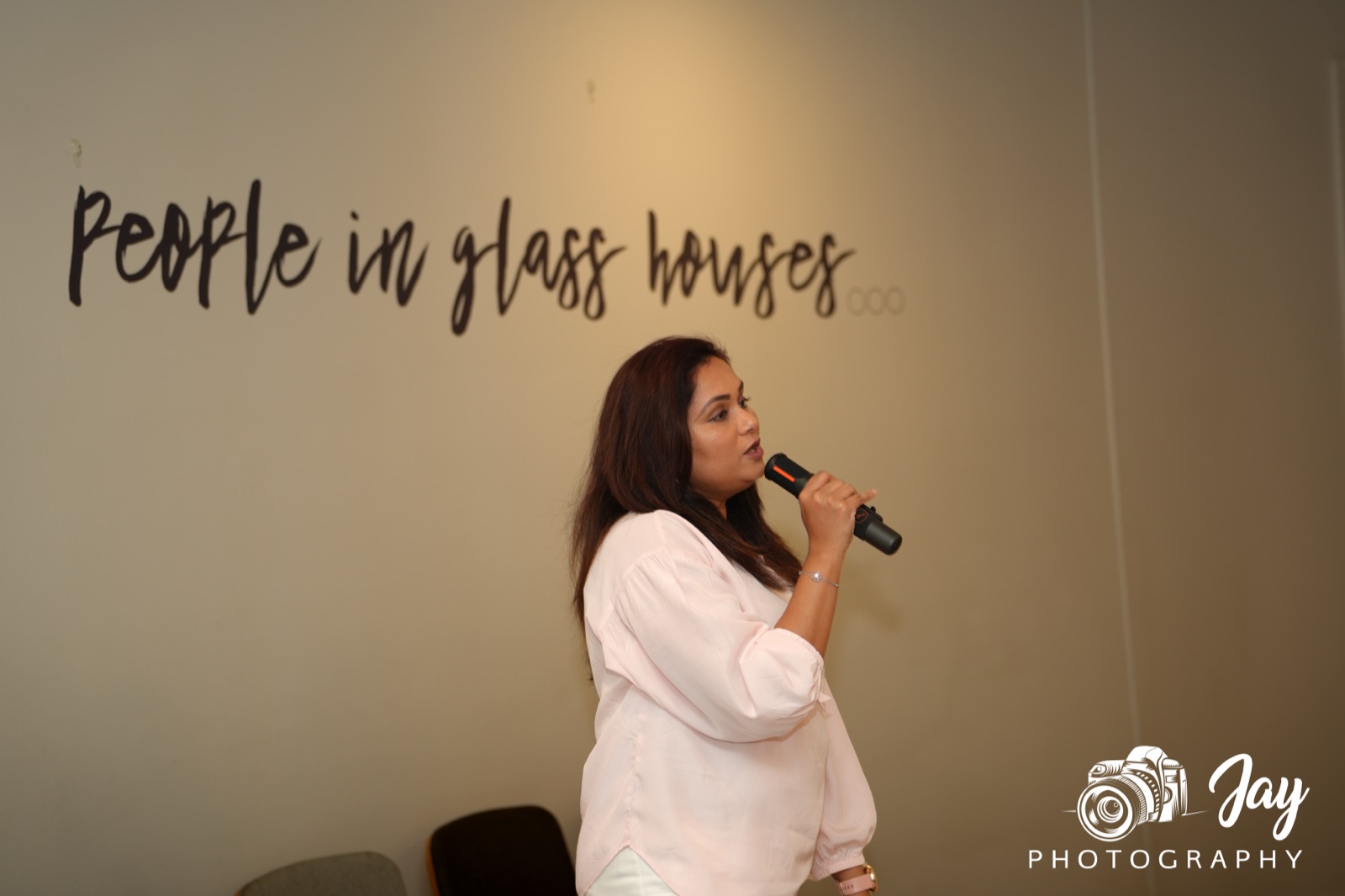 BGN Caulfield member speaking into a microphone beside the venue's wall mural