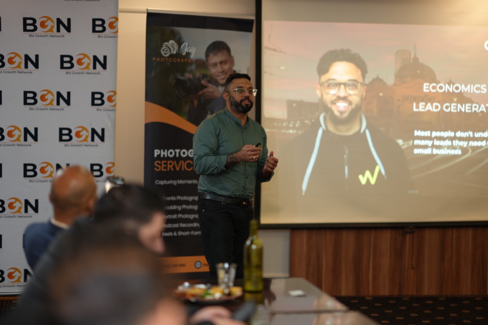 BGN member presenting to the room, cocktail tables in the foreground
