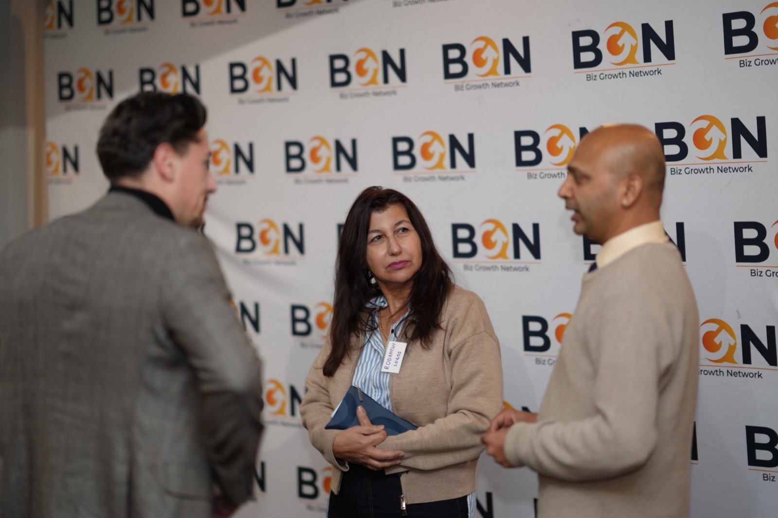 BGN members in warm conversation at a Biz Growth Network event backdrop