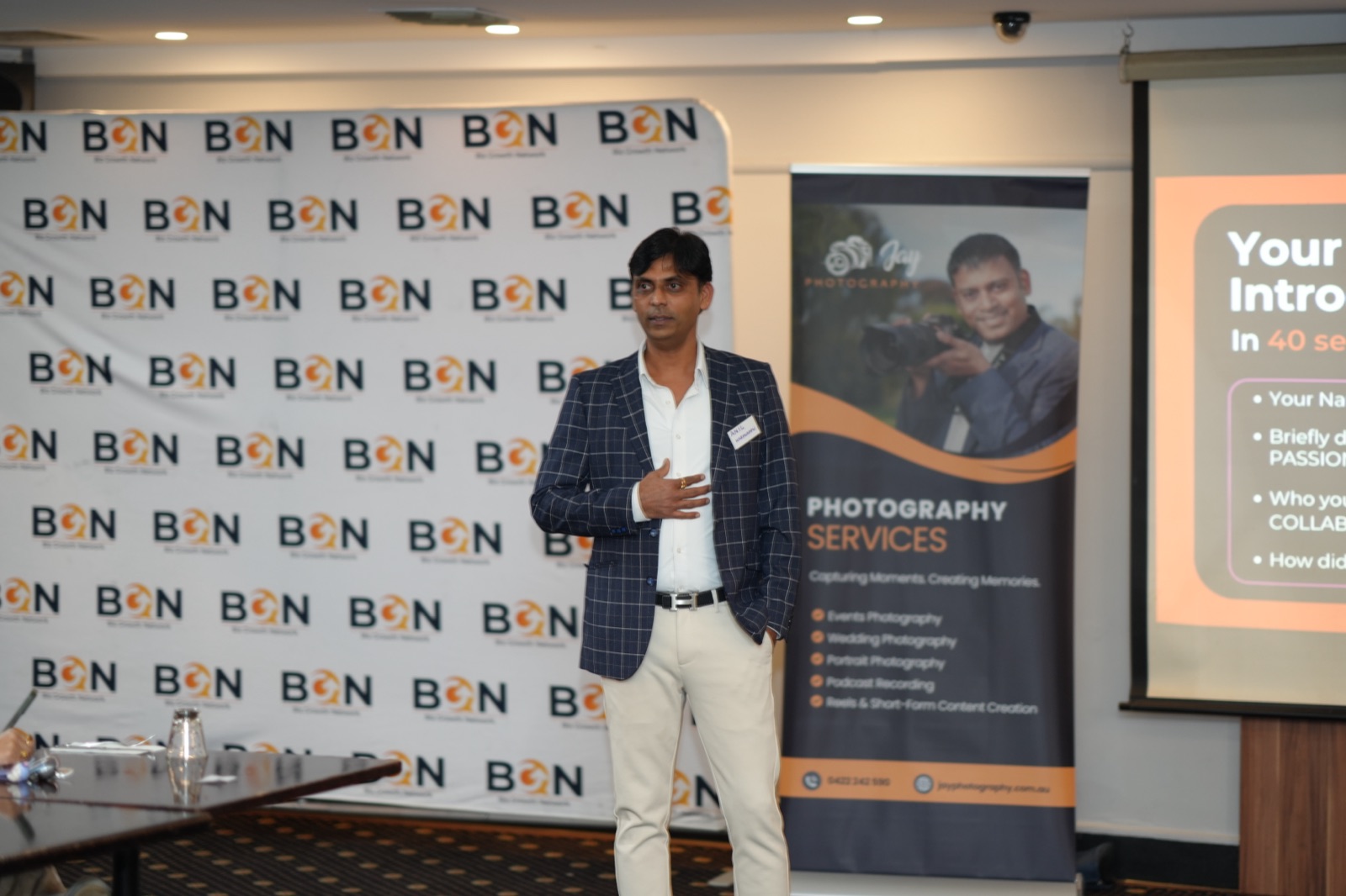 BGN member speaking mid-introduction, gesturing as he addresses the room